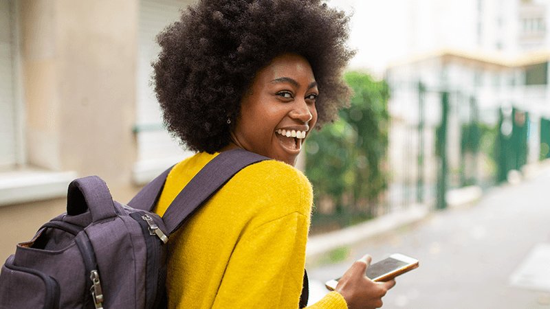 young person probably a student on their phone on the way to a train station using their 1625 railcard